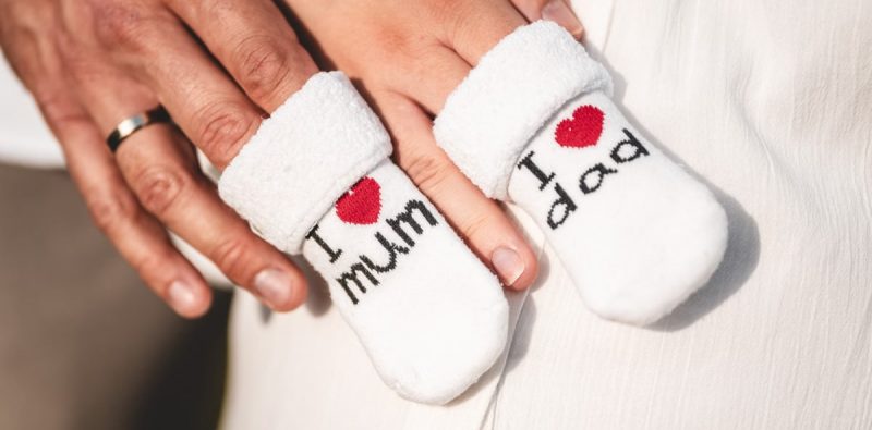 Close-up of parents holding baby booties that say 'I love mum' and 'I love dad'.